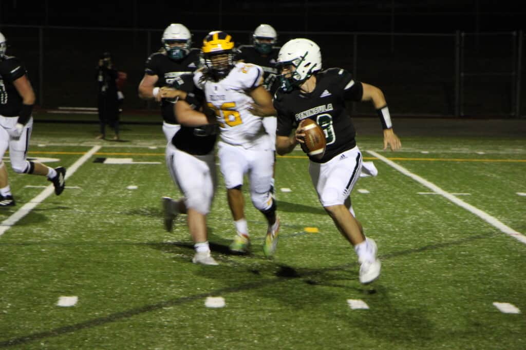 Peninsula quarterback races around left end during a season-opening loss to Bellevue.