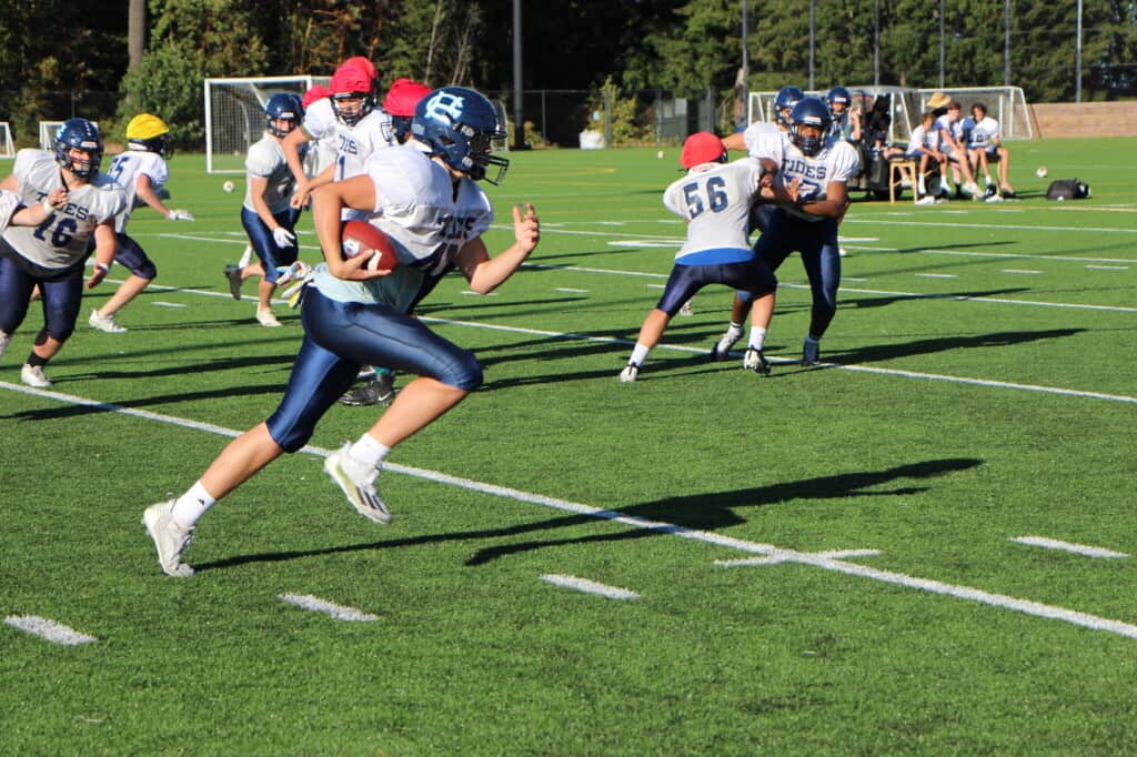 A Gig Harbor player gets a few blocks while running the ball in practice.