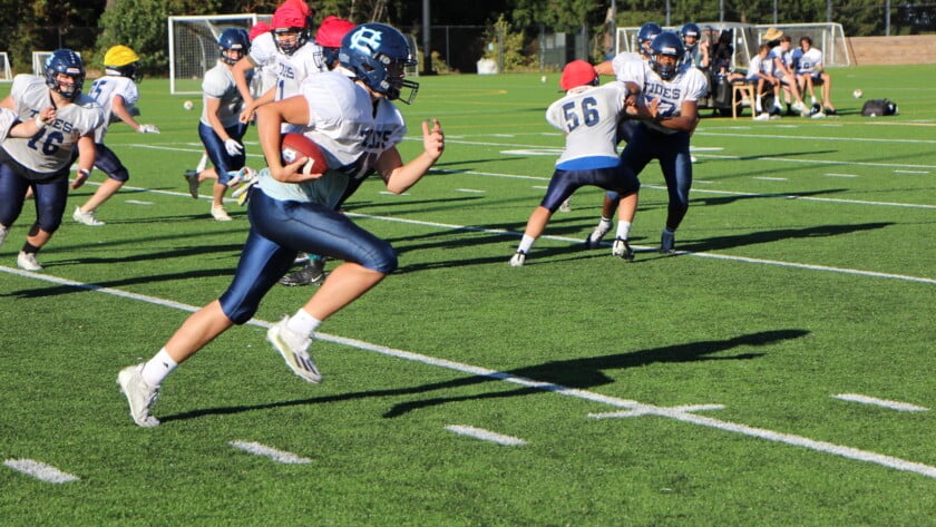 A Gig Harbor player gets a few blocks while running the ball in practice.