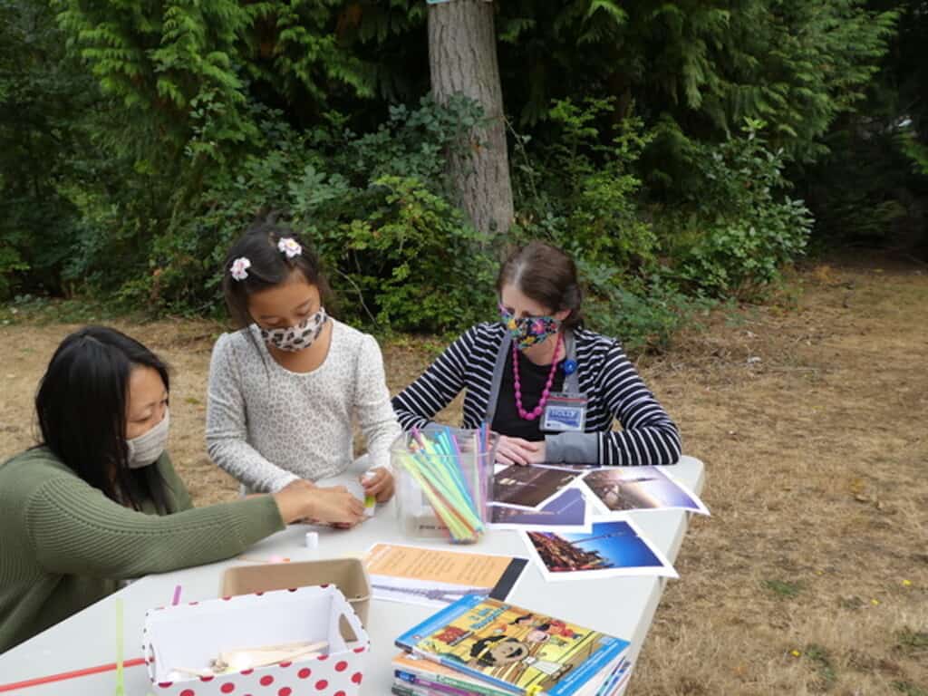 Emerson Delapena, 7, gets help from her mother Anna Delapena, as librarian Holly Smith looks on.