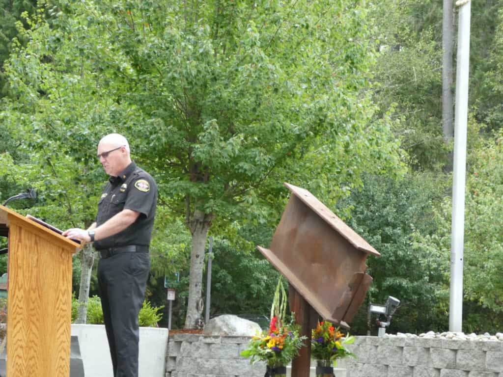 Gig Harbor Fire & Medic One Chief Dennis One speaks at the department's 9/11 memorial honoring the 20th anniversay of the terrorist attacks. Behind him is a relic of the World Trade Center.