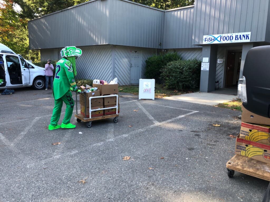 Captain Seahawk (Gig Harbor resident Wallace Watts) wheels in a cartload of food donated to FISH.