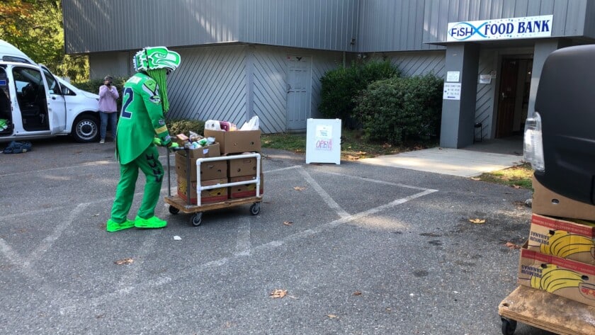 Captain Seahawk (Gig Harbor resident Wallace Watts) wheels in a cartload of food donated to FISH.