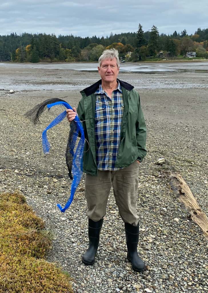 Shoreline resident Carl Marlow, in front of his house, shows some of the aquaculture debris he has cleaned from the lagoon.