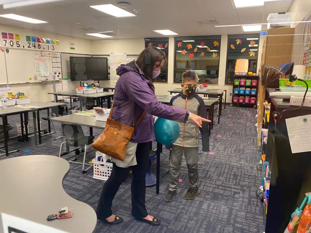 Swift Water Elementary School student Lukas Rimmele and his mother Katja Rimmele, seen through a glass partition, tour Lukas’ fourth-grade classroom during an open house at the school.