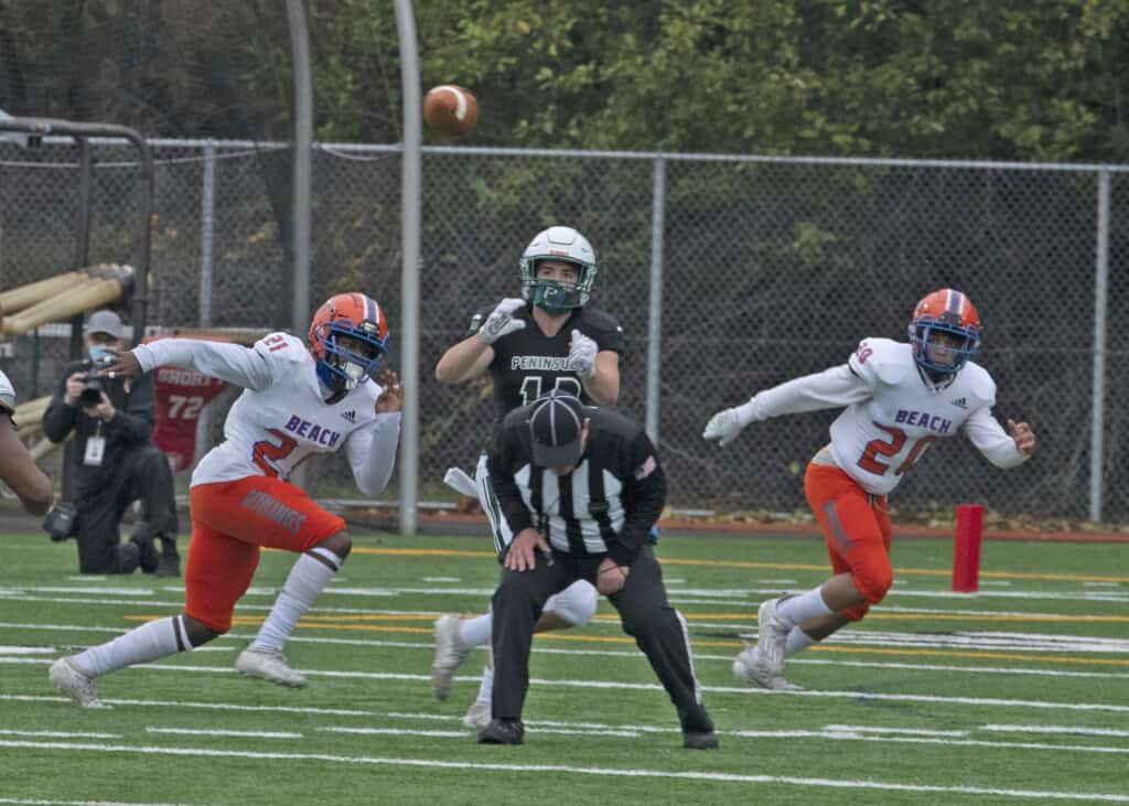 An official ducks under a pass headed for Peninsula receiver Austin Hansen.