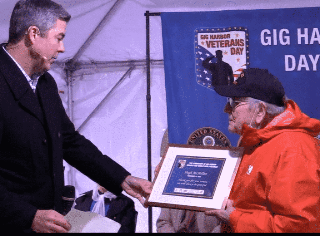 Emcee Greg Copeland (left) KING TV news anchor, presents a certificate of appreciation to Hugh McMillan, US Navy vet and retired CIA agent