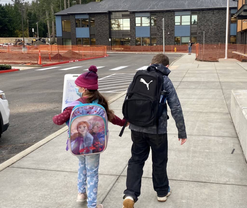 Siblings Madison (left) and Mason Lukenbach walk into the new Artondale Elementary School on Nov. 22, 2021, the first day the building was open for classes.