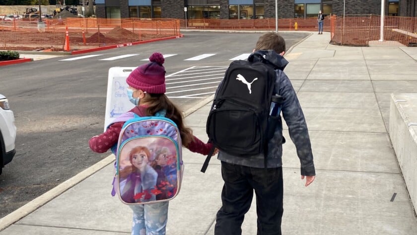 Siblings Madison (left) and Mason Lukenbach walk into the new Artondale Elementary School on Nov. 22, 2021, the first day the building was open for classes.