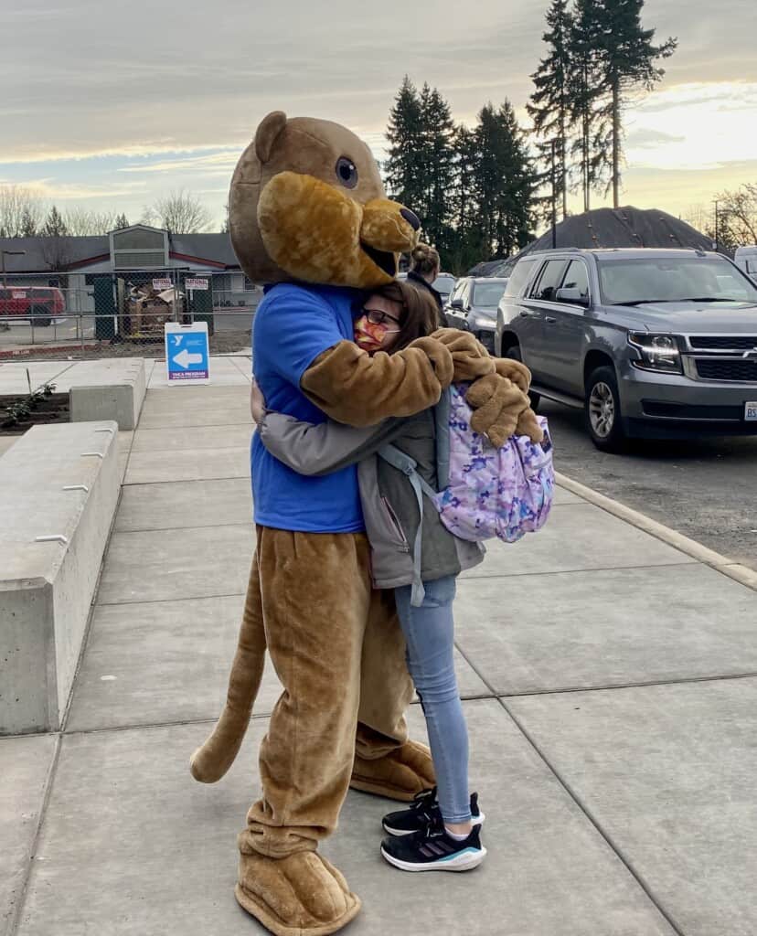 Ollie the Otter gets a hug from student Audrey Jones on the first day of classes at the newly constructed Artondale Elementary School building, on Nov. 22, 2021.