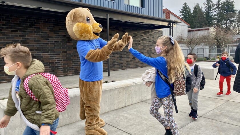 Sophia Sandquist gives a high five to Ollie the Otter on the first day of classes at the newly constructed Artondale Elementary School building, on Nov. 22,