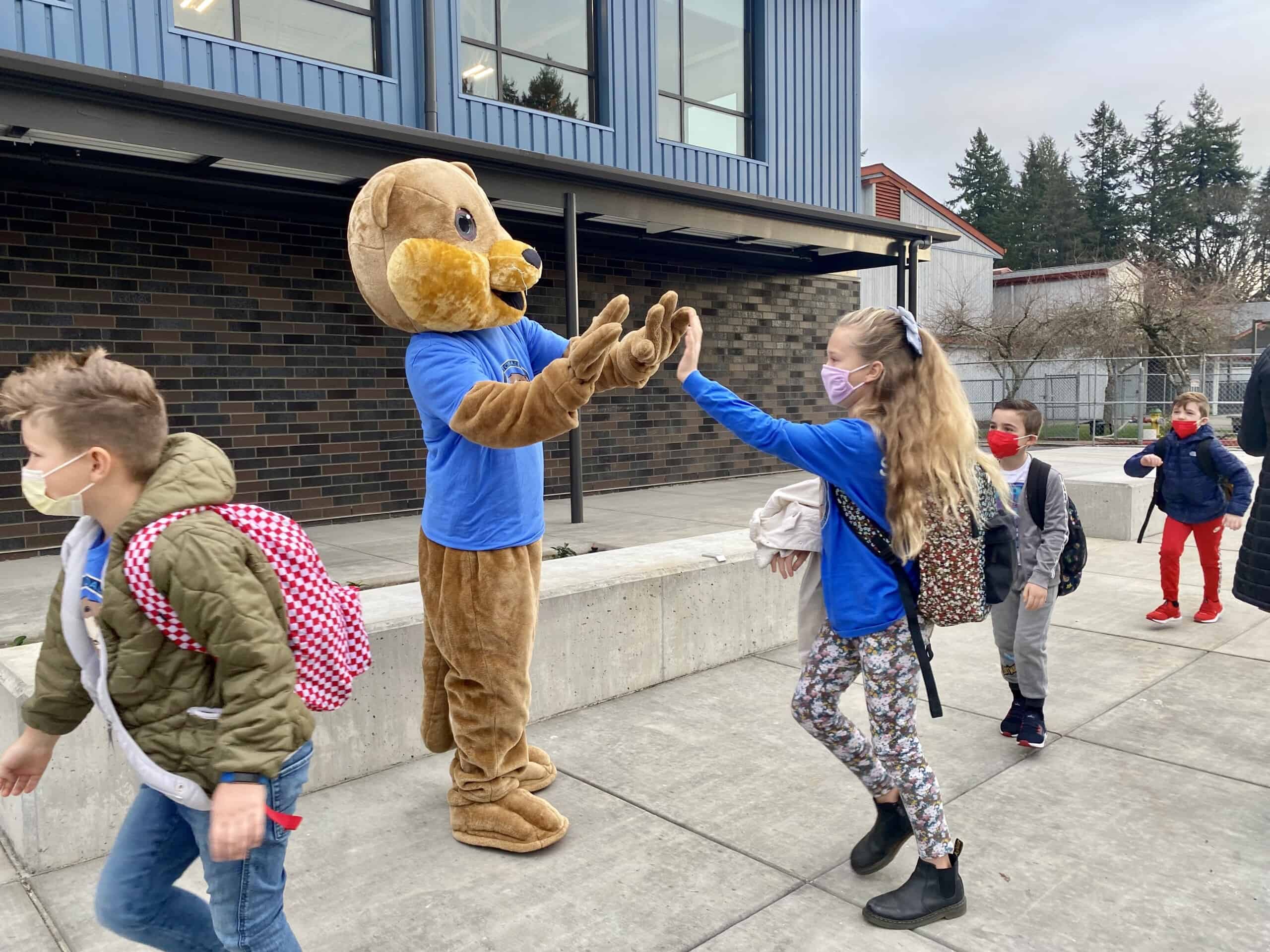Sophia Sandquist gives a high five to Ollie the Otter on the first day of classes at the newly constructed Artondale Elementary School building, on Nov. 22,