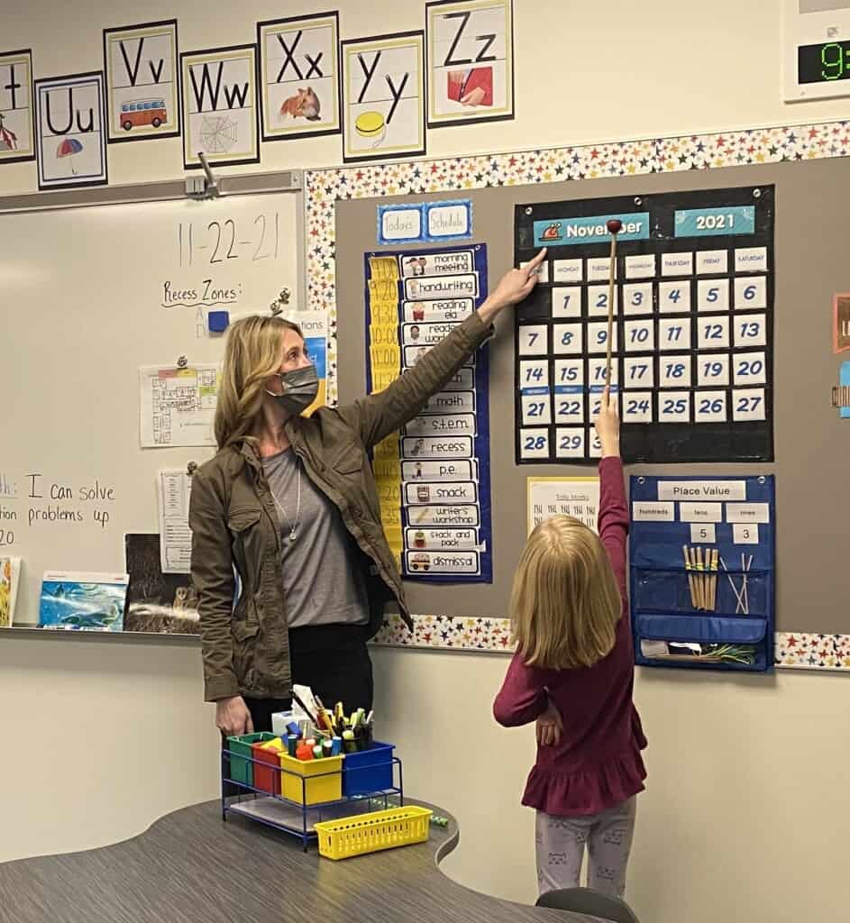 Student Aliyah Myhre helps her teacher Rashelle Pratz with the daily calendar on Nov. 22, 2021, the first day of classes at the newly constructed Artondale Elementary School building. Teachers moved classroom materials over the past two weekends to be ready for the students’ move from the old Artondale