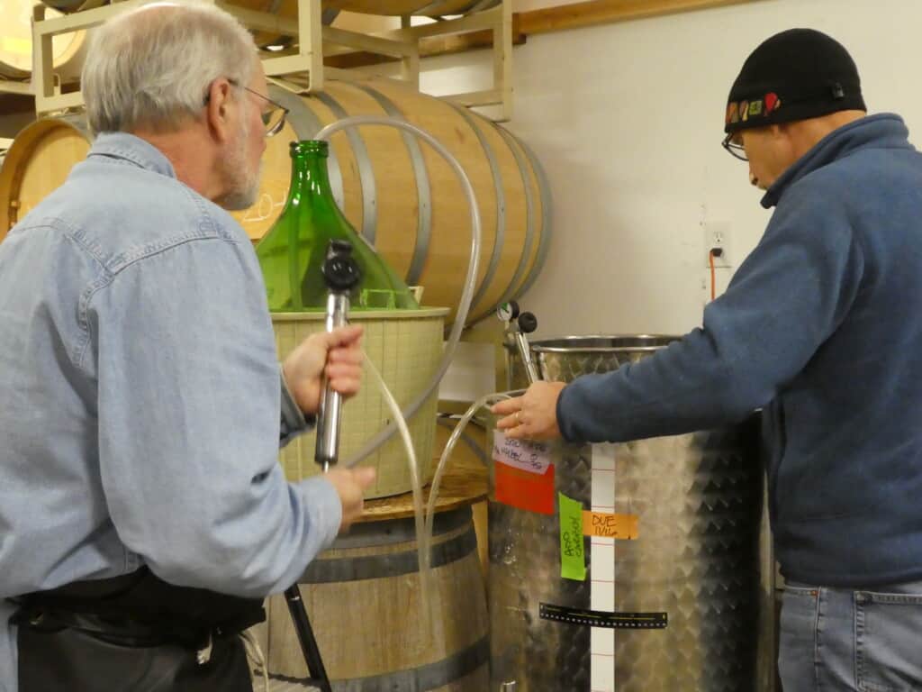 Two Loons Winery owners Peter Knecht and Mike Simpson topping the wine.