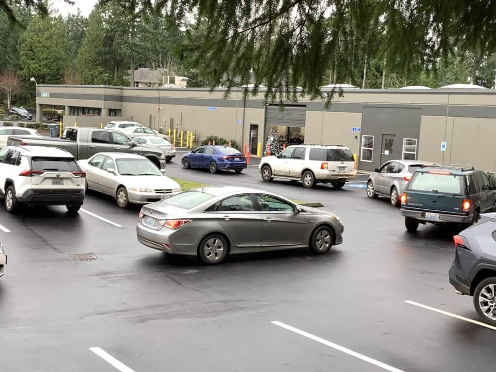 Cars line up in the warehouse parking lot.