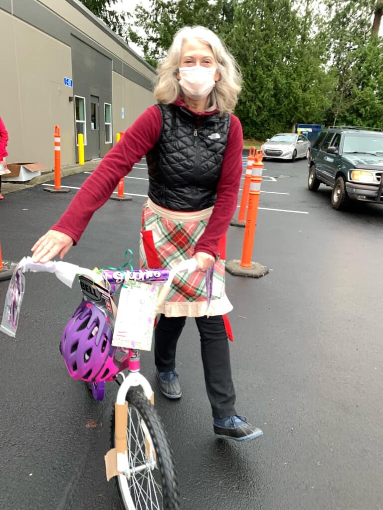 Volunteer Joyce Winge wheels a bike to a car.