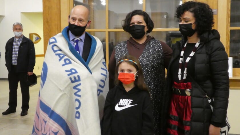 Mayor Kit Kuhn wrapped in the blanket presented to him by Puyallup Tribal Councilmember Anna Bean, Tribal Language Program Director Amber Hayward and six-year old Tribal member Zoe Keating