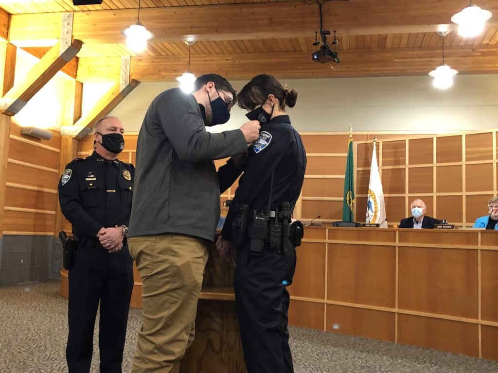 New police officer Kelsey Burgin-Dove's husband pins on her new badge after she was sworn in by Mayor Kit Kuhn.