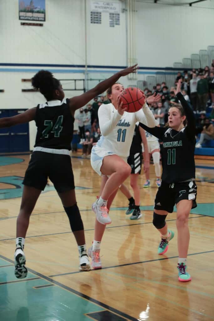 Riley Peschek slices for a shot between Peninsula's Kaylia Heidelberg (32) and Grace Richardson (24).