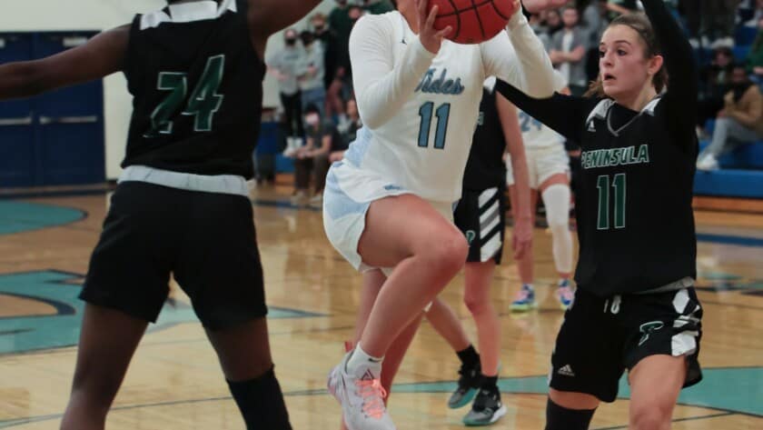 Riley Peschek slices for a shot between Peninsula's Kaylia Heidelberg (32) and Grace Richardson (24).