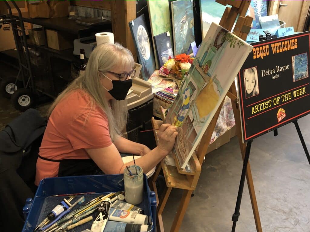 When lines formed for takeout meals at the restaurant, BBQ2U invited painters and authors to chat up the customers, giving patrons a look at their work in the process, and it continues today. On Sunday, Debra Rayne was there painting.