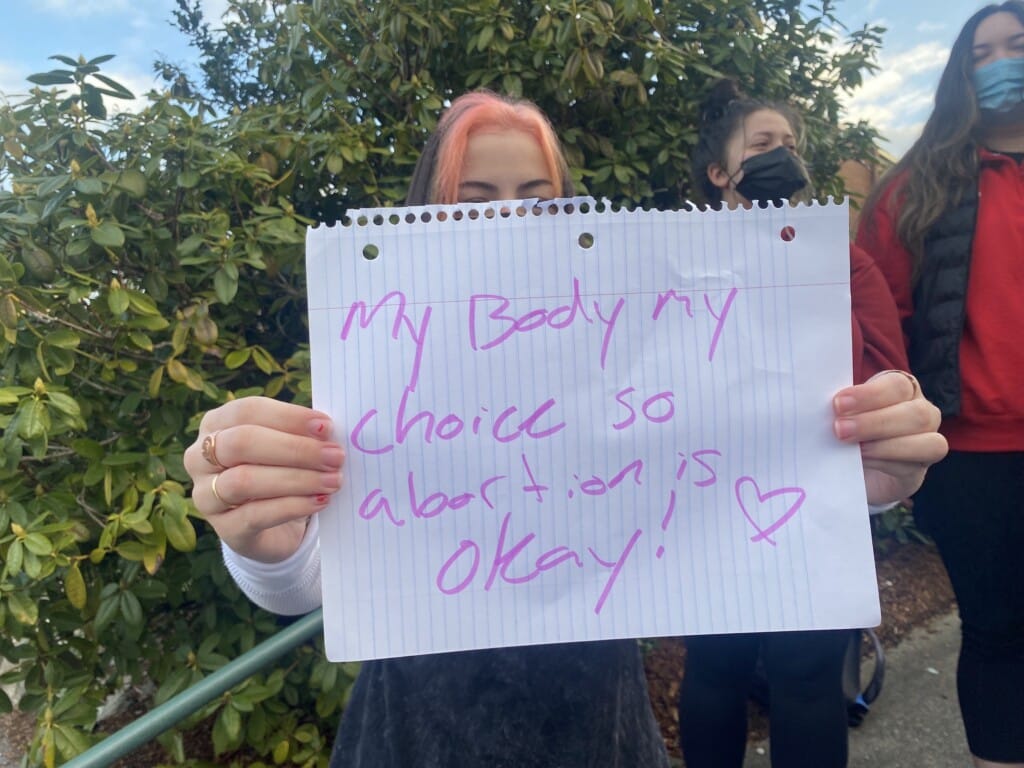 A student holds a pro-abortion sign on Wednesday outside Peninsula High School as part of a group counter-protesting another group across the street calling for an end to the school mask mandate.