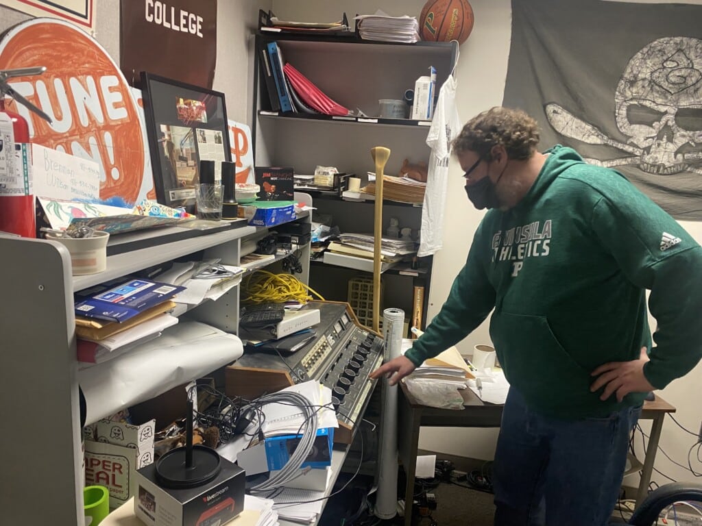 Spencer Abersold, station manager of KGHP-FM, looks over an obsolete broadcast console in his office on Thursday, Feb. 3, 2022. The radio station is based at Peninsula High School in Gig Harbor and owned by Peninsula School District.