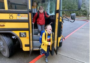 Discovery Elementary School students get off the bus Monday, March 14, 2022, the first day of school since Gov. Jay Inslee lifted the state’s indoor mask mandate.