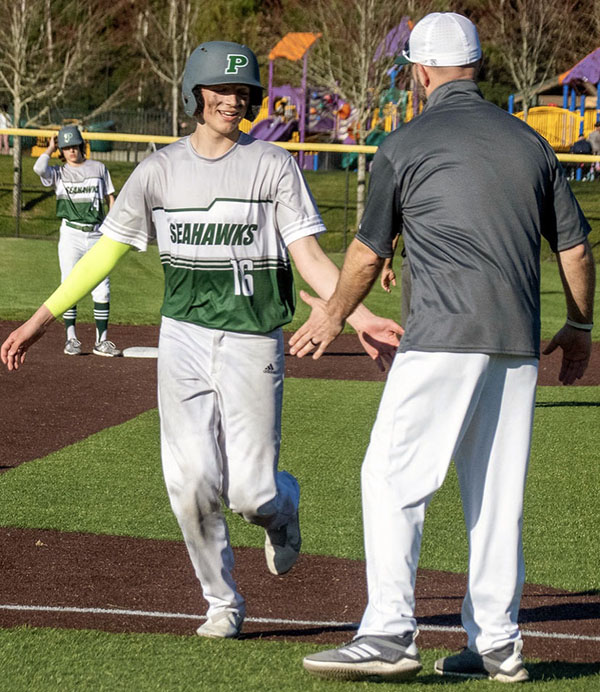 Coach Michaerl Johnson congratulates sophomore Aiden Deschenes during a recent game.