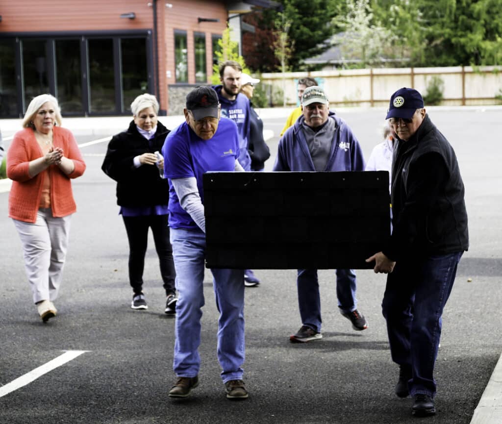 Rotarians carry a new Little Food Pantry to its new home at Peninsula Life Church in Purdy on Friday, April 29, 2022.
