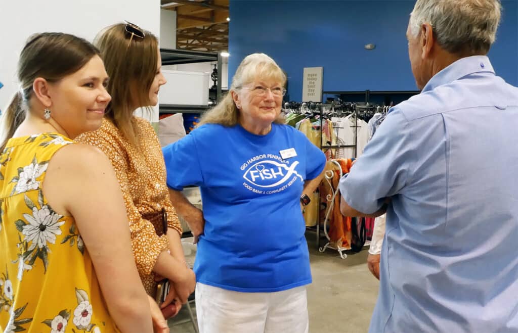 GIg Harbor Peninsula FISH Food Bank founder Jan Coen, center in blue shirt, visits with volunteers last week.