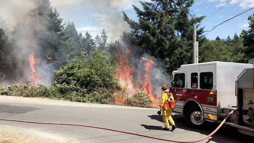 A fire crew from Gig Harbor Fire & Medic One fights a brush fire in 2019 at Murphy Drive and East Bay Drive.
