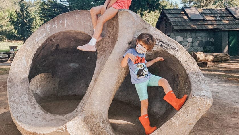 Two children sit on a concrete sculpture shaped like a snail shell.