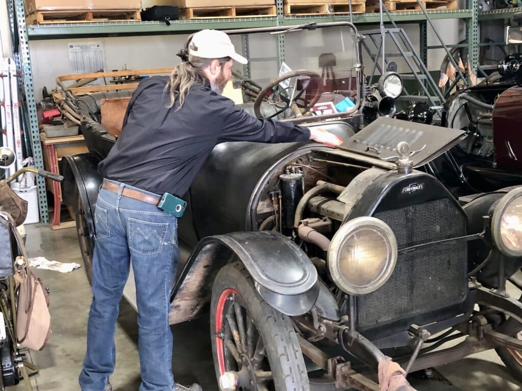 Aviation mechanic Bob Johnson wipes dust from his 1916 Chevrolet. He likes restoring cars as much as planes ("Anything old," he says), and has a handful at museum.