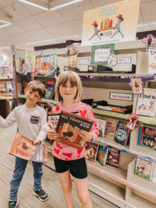 Room with bookshelves and two kids holding books