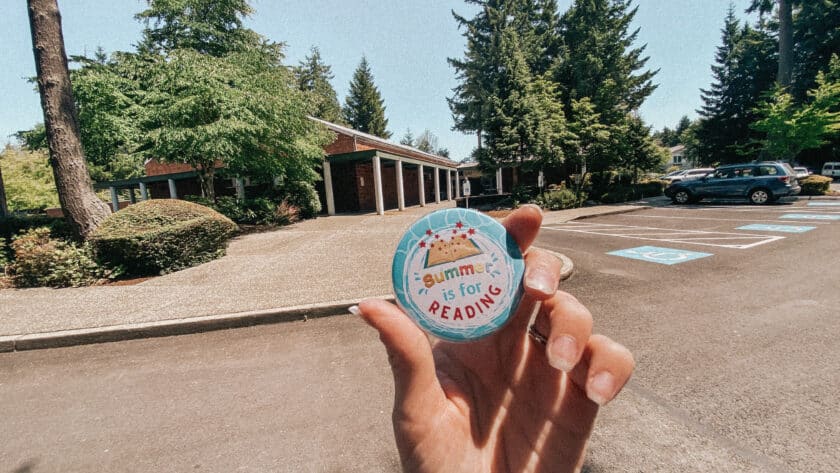 A round button in focus with a brick library building in the background