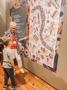 woman showing boy posters on the wall in museum