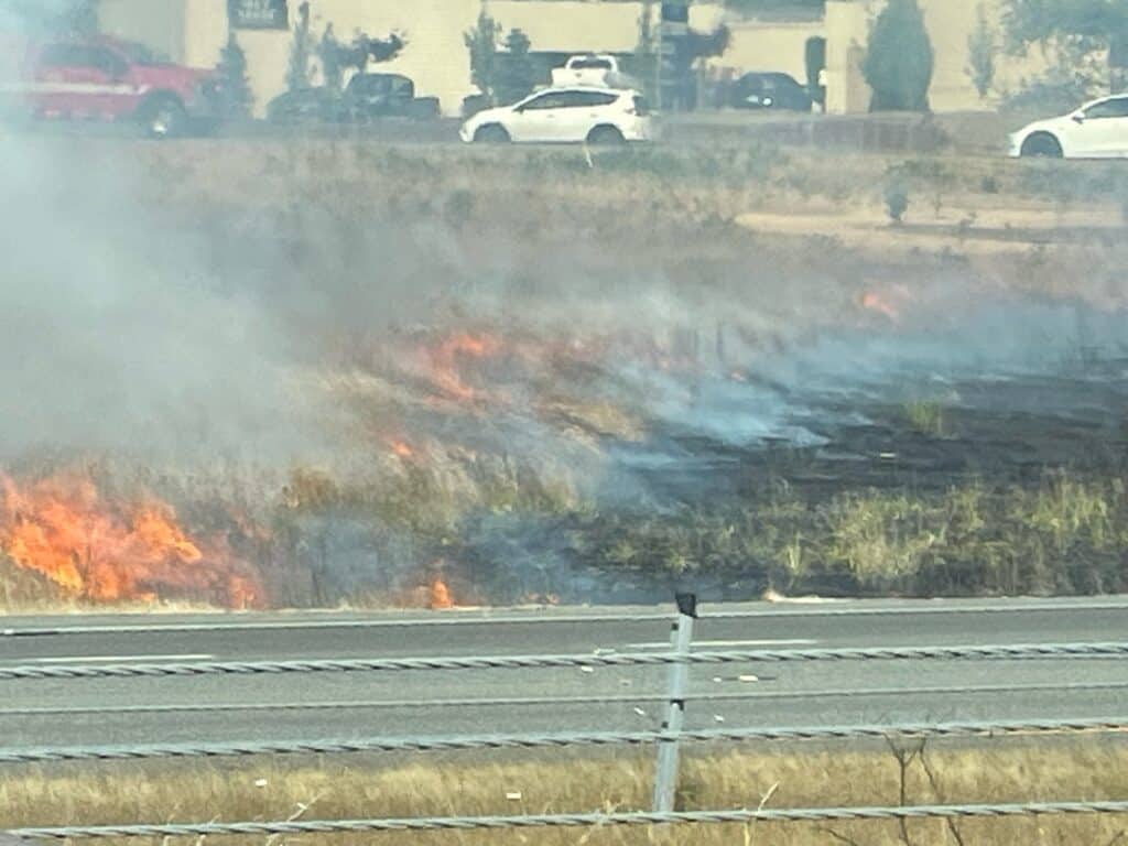 A brush fire burns Tuesday between Highway 16 and the Wollochet Drive ramp.