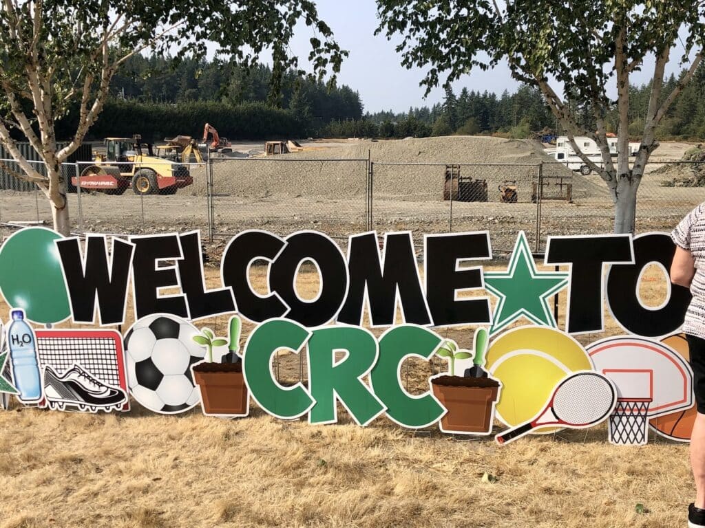 Construction equipment and progress is visible behind welcome banner for event.