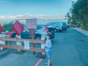 This is a photo of signs, a wooden barrier and some parked cars.