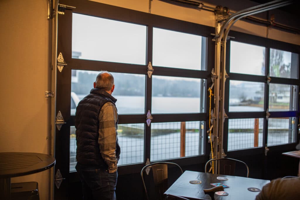 Hal Haase admires the view from the newly installed garage doors. Customers can now enjoy both indoor and outdoor seating, offering views of the sunset and the chance to observe orcas and wildlife.
