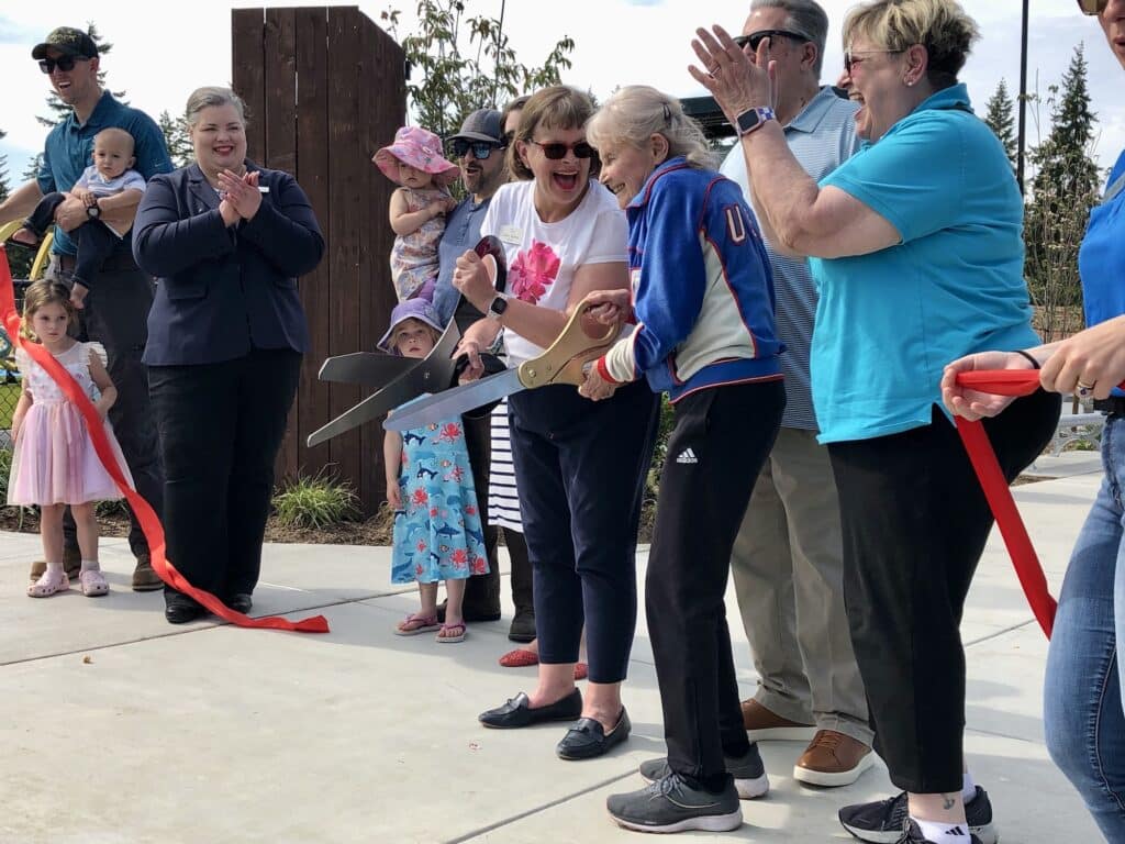 Mayor Mary Barber and Doris Heritage cut the ribbon, joined by city council members and staff.