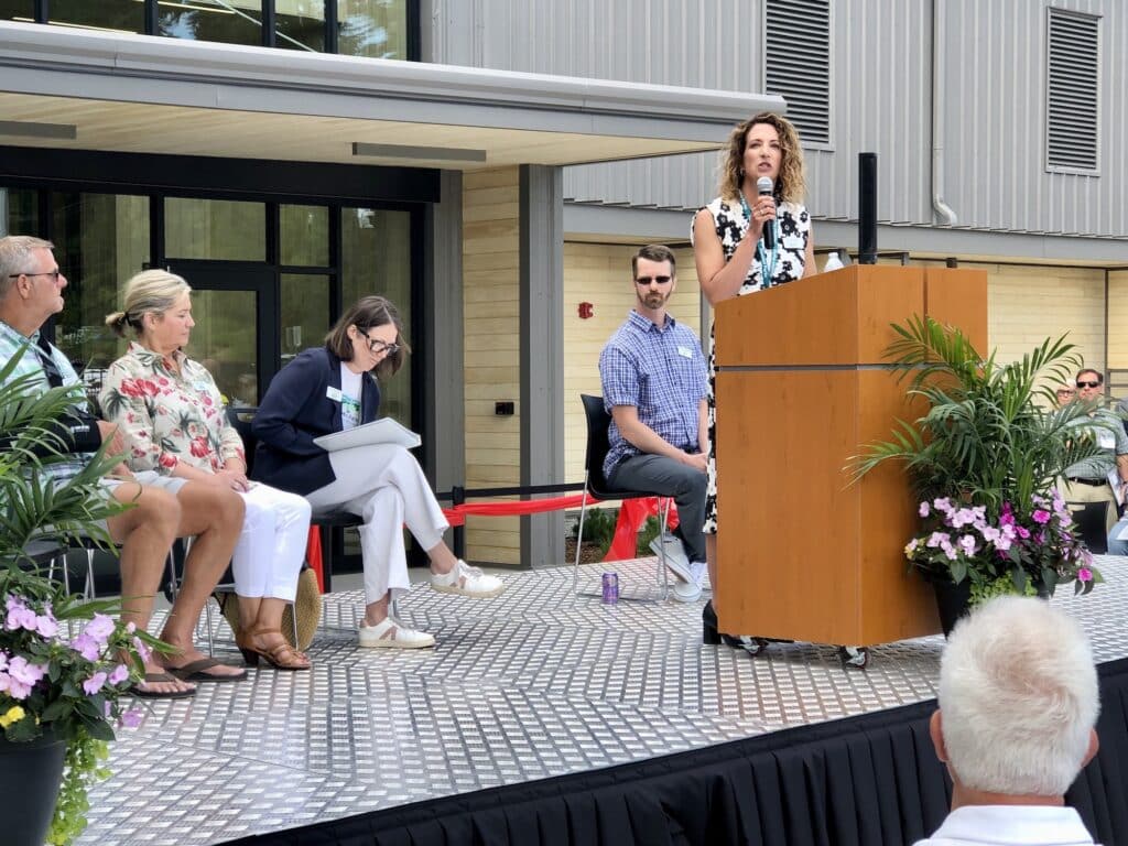 Executive Director Ally Bujacich addresses the crowd during the ribbon cutting. behind her are board members Missy Hill, Lauren Kingsbury and Billy Sehmel. Kurt Grimmer and Steve Nixon are not visible.